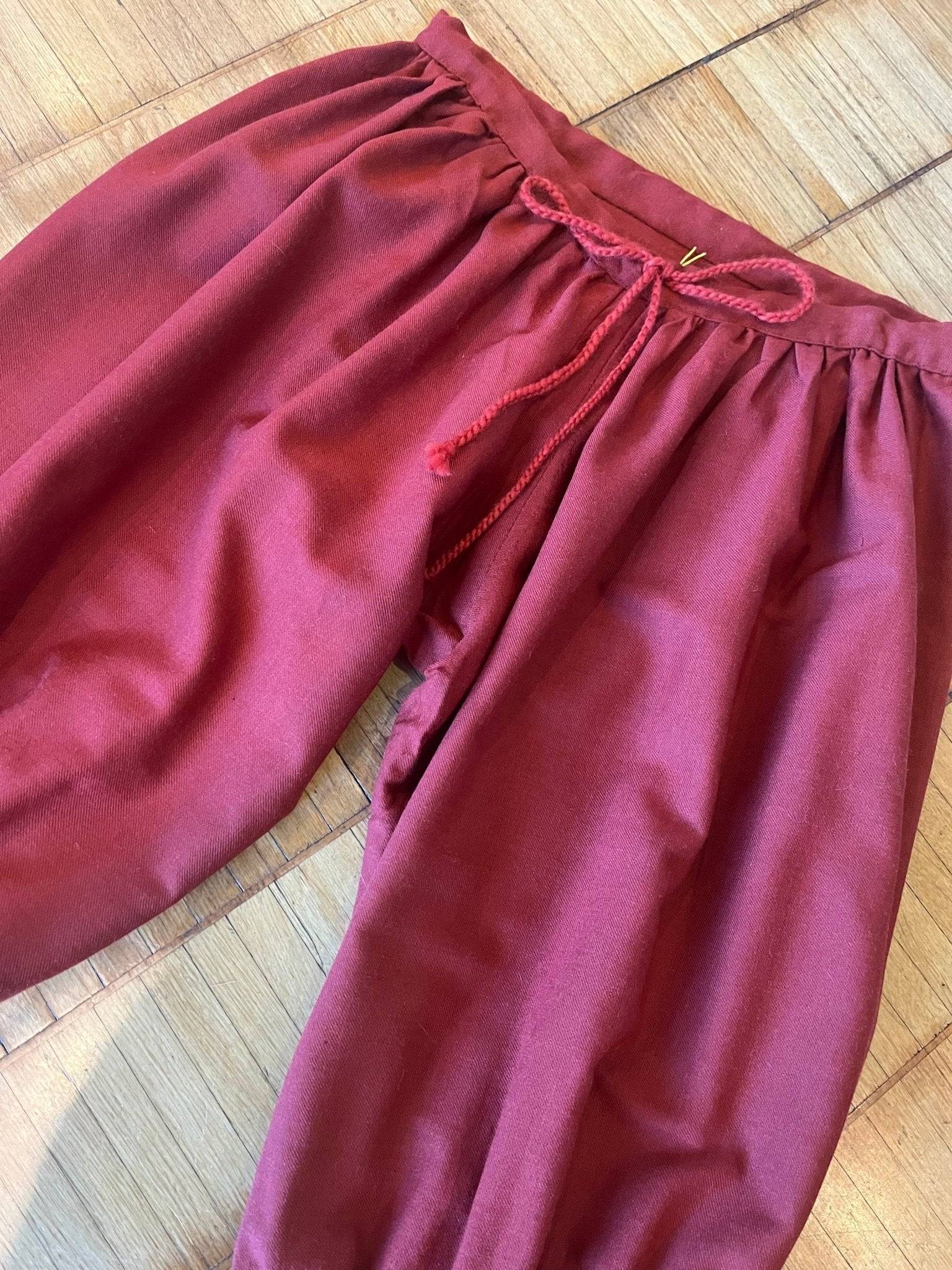 Red woolen Viking pants laid flat on wooden floor